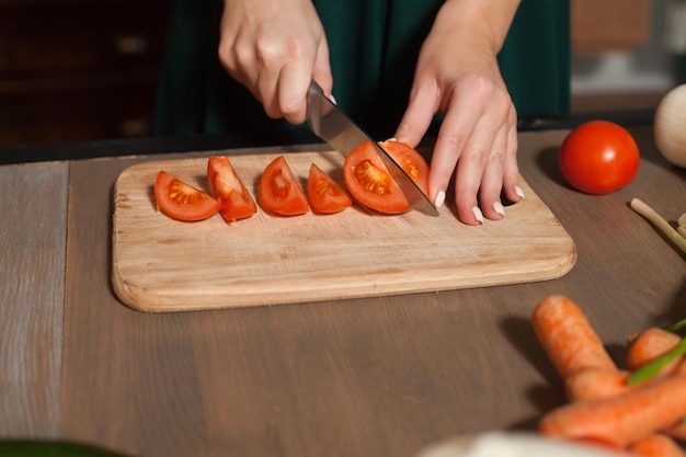 Tomaten snijden wordt door vrouw aan de houten tafel gedaan