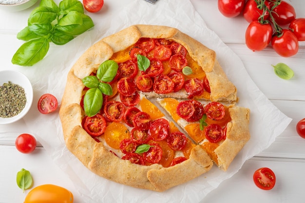 Tomatengalette of taart met kaas en kruiden op een witte houten achtergrond Vegetarische schotel