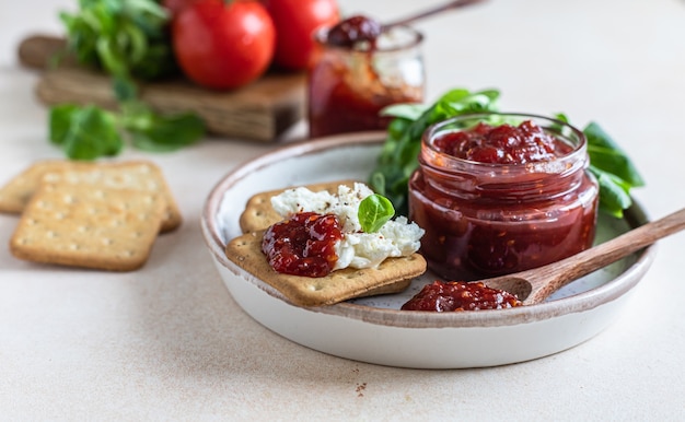 Tomatenjam confiture of saus met crackers en groene blaadjes salade bijzondere hartige jam