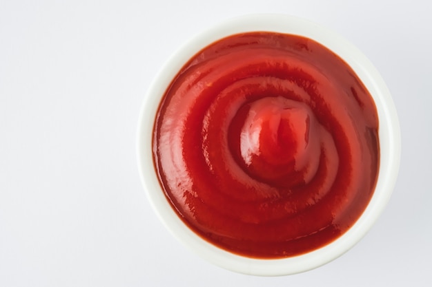 Tomatenketchup in keramische kom op witte achtergrond.