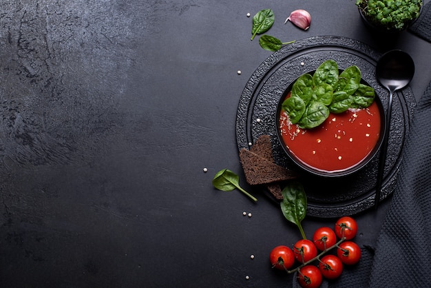 Tomatenpuree soep met spinazie in een zwarte kom, bovenaanzicht