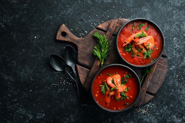 Tomatenroomsoep met garnalen in een zwarte kom Zeevruchtenmenu Bovenaanzicht Rustiek