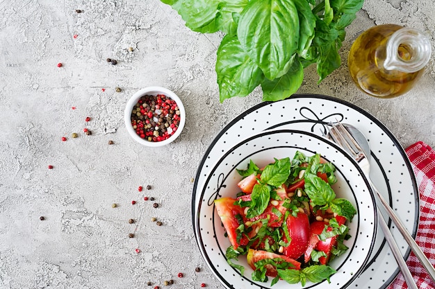 Tomatensalade met basilicum en pijnboompitten in kom - gezond vegetarisch veganistisch dieet biologisch voedselvoorgerecht. Bovenaanzicht Plat leggen