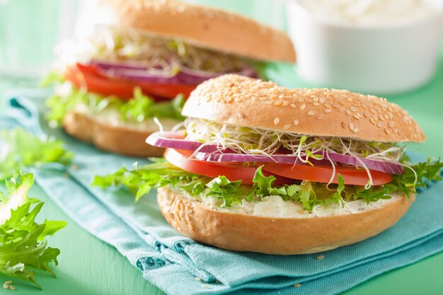 Tomatensandwich op bagel met roomkaas, ui en sla