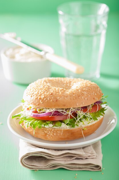 Tomatensandwich op bagel met roomkaas, ui en sla