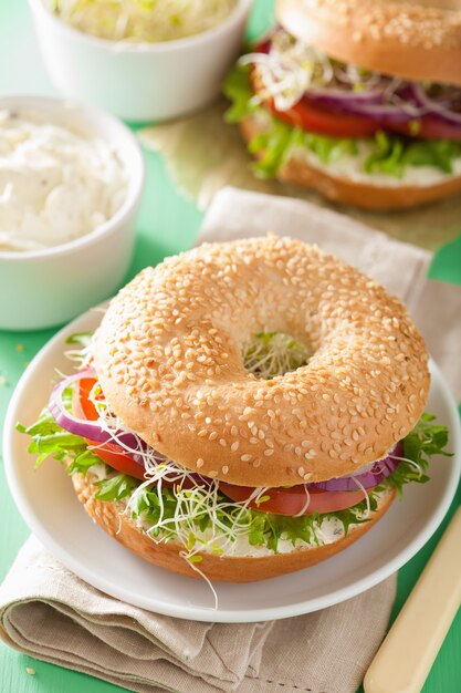 Tomatensandwich op bagel met roomkaas, ui en sla