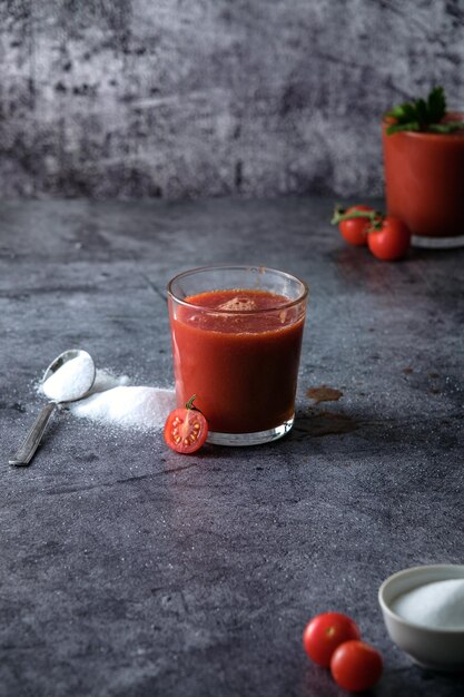 tomatensap, giet tomatensap in een glas, spatten tomatensap, op een grijze achtergrond