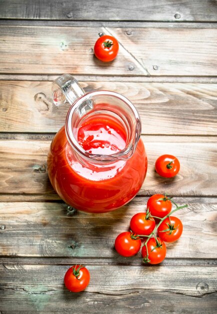 Foto tomatensap in een kruik en verse tomaten