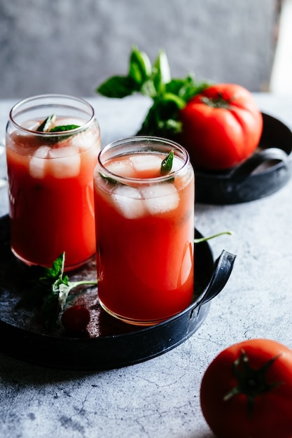 Tomatensap met ijs in een glas op een grijze achtergrond