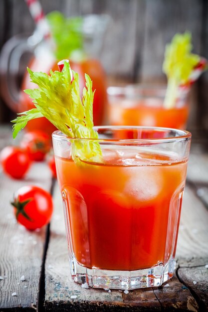 Tomatensap met selderij en ijs in glazen op een houten tafel