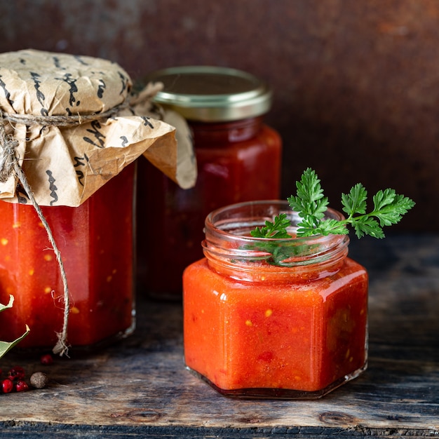 Tomatensaus in een glazen pot en ingrediënten, close-up. Vierkant