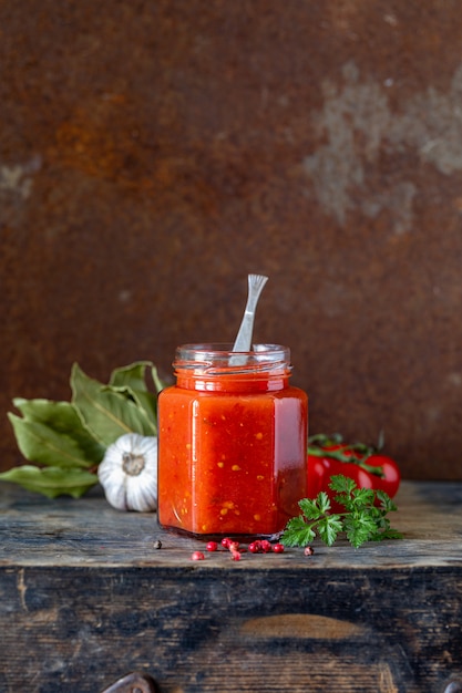 Tomatensaus in een glazen pot en ingrediënten. kopieer ruimte