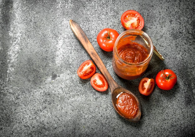 Tomatensaus in glazen pot met lepel.