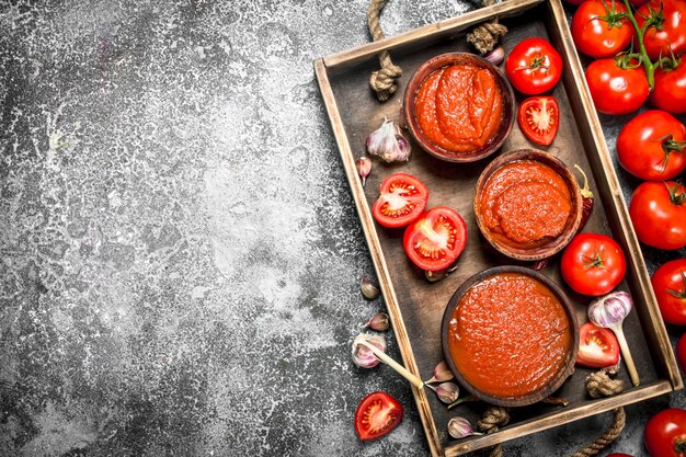 Tomatensaus met kruiden, specerijen en knoflook op houten bakje.