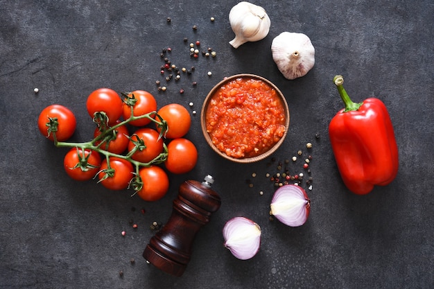 Tomatensaus met peper en knoflook op een donkere betonnen achtergrond.