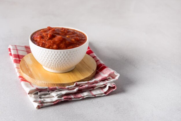 Tomatensaus of zelfgemaakte ketchup gezonde groentesaus in witte kom op houten dienblad kopie ruimte