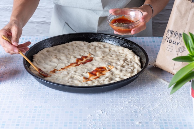 Tomatensaus op een zelfgemaakte pizza doen