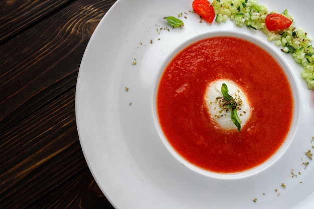 Tomatensoep in een witte plaat op een houten ondergrond