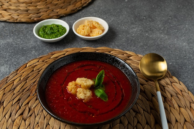 Tomatensoep in zwarte kom op grijze stenen tafel