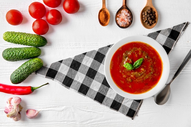 Tomatensoep met basilicum, peper, knoflook en komkommer op houten achtergrond. Spaanse Gazpacho Soep.