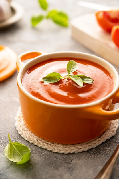 Tomatensoep met verse basilicum in oranje kom Heldere achtergrond Gezonde voeding concept