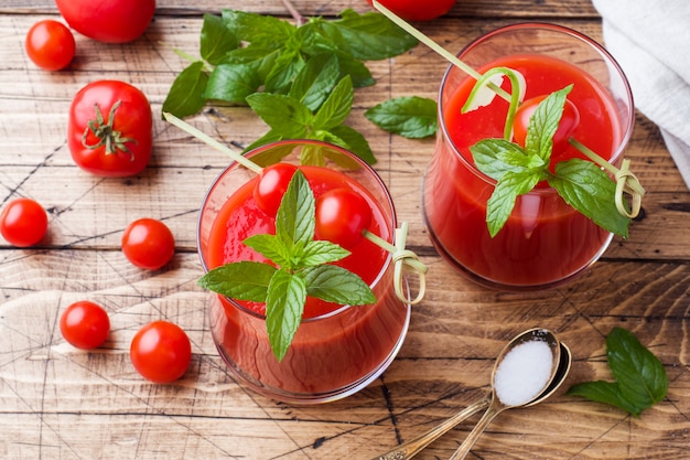 Tomatesap met munt in glas en verse tomaten op een houten tafel. Gezond natuurvoedingconcept.