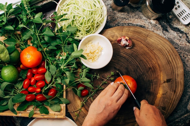 Tomato being sliced on a wooden board for an organic salad recipe