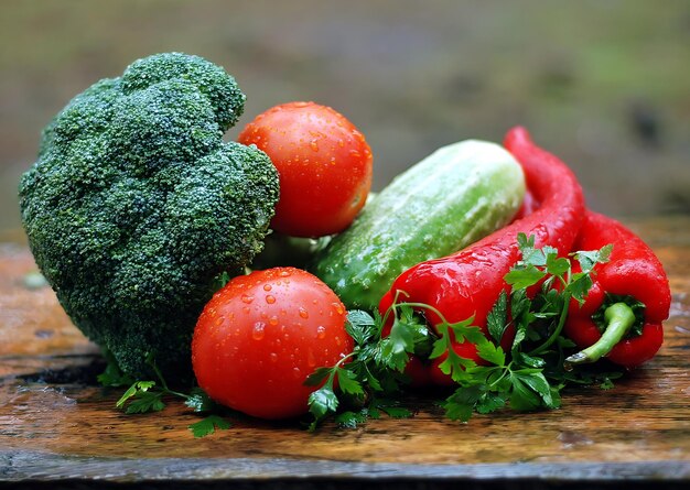 A tomato is on a table with vegetables including broccoli, tomatoes, and cucumber.