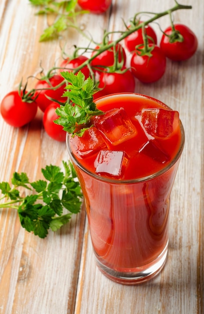 写真 トマトジュースと木製のテーブルの上のトマト