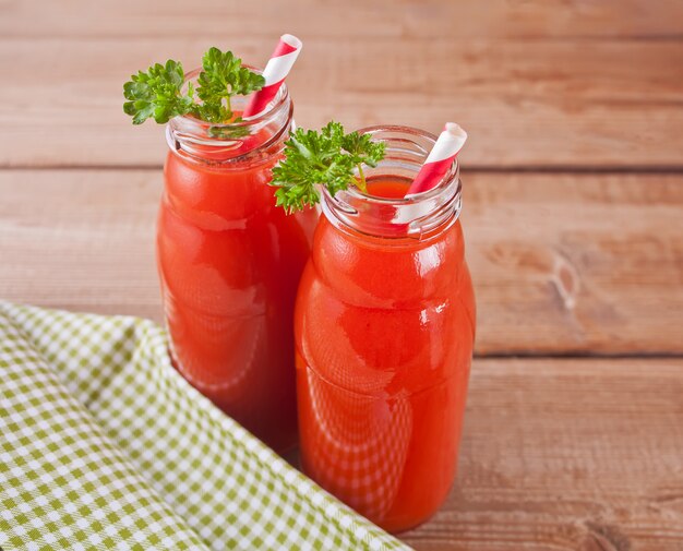 Tomato juice in bottles with parsley and salt on the wooden table