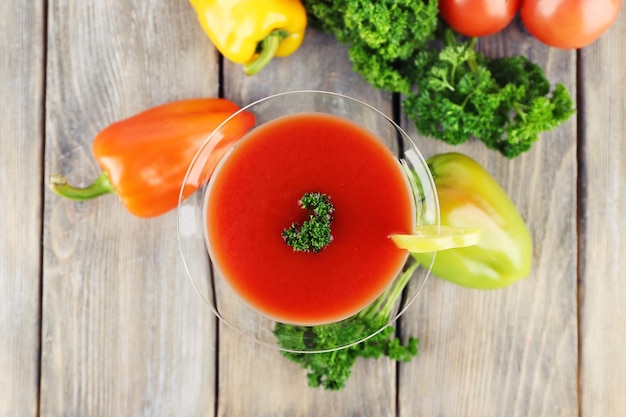 Tomato juice in goblet pepper parsley and fresh tomatoes on wooden background