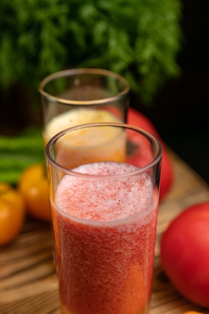 Tomato juice on a table near the green and yellow and red tomatoes