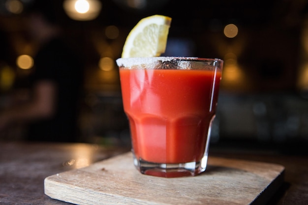 Tomato juice with lemon on a wooden stand in a restaurant