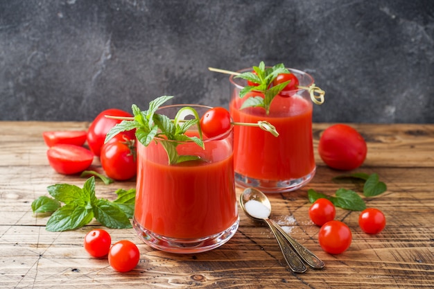 ガラスと木製のテーブルにフレッシュトマトのミントとトマトジュース。健康的な有機食品のコンセプト