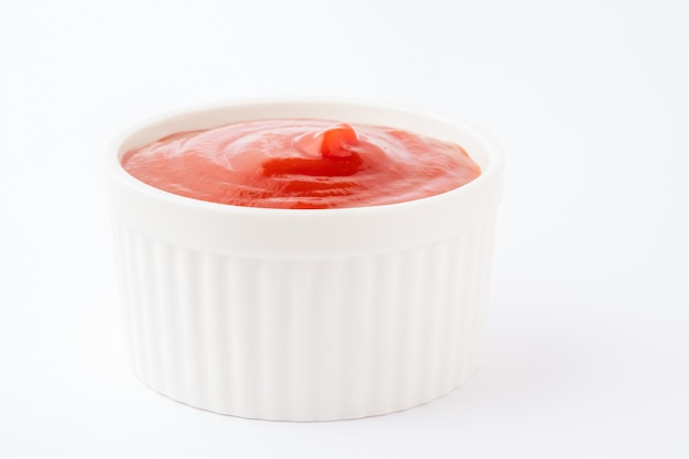 Tomato ketchup in ceramic bowl on white background.