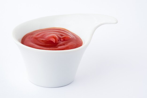 Foto ketchup di pomodoro in ciotola di ceramica su sfondo bianco.