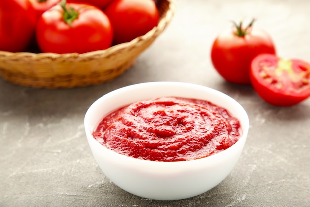 Tomato ketchup sauce in a bowl with tomatoes