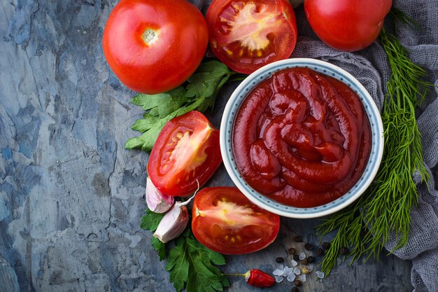 Tomato ketchup sauce on concrete background. Selective focus