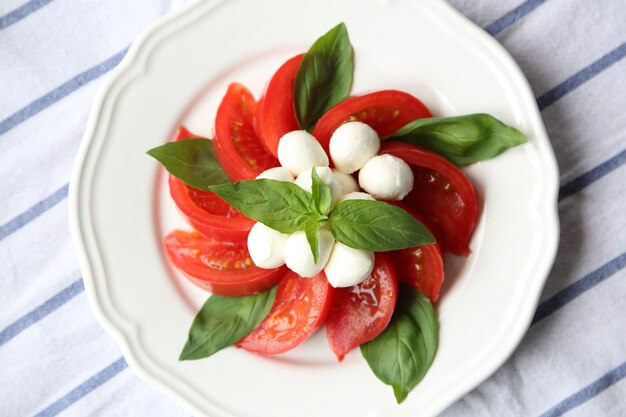 Foto mozzarella e pomodoro leaf del pomodoro su un fuoco selettivo della luce naturale di vista superiore del piatto bianco