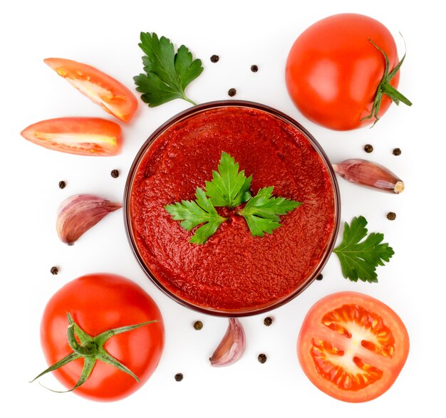 Photo tomato paste in a plate with parsley leaves, tomatoes, garlic and pepper