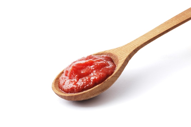 Tomato paste on a wooden spoon isolated on white background