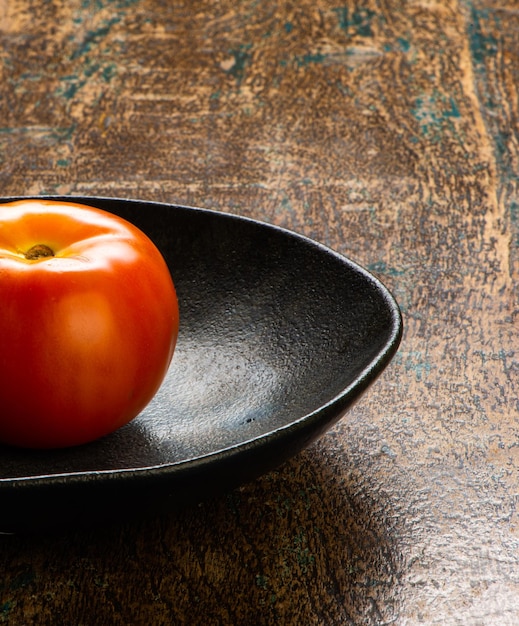 Tomato in a rustic plate on a wooden table