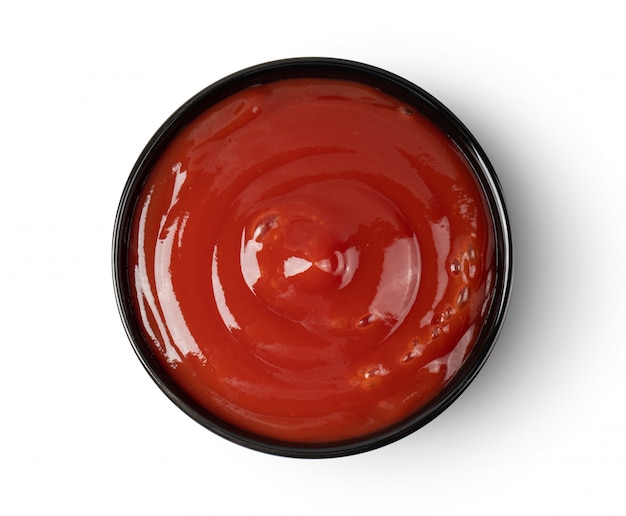 Tomato sauce in black bowl on white wall. 