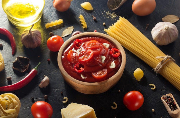 Tomato sauce in bowl on black background texture