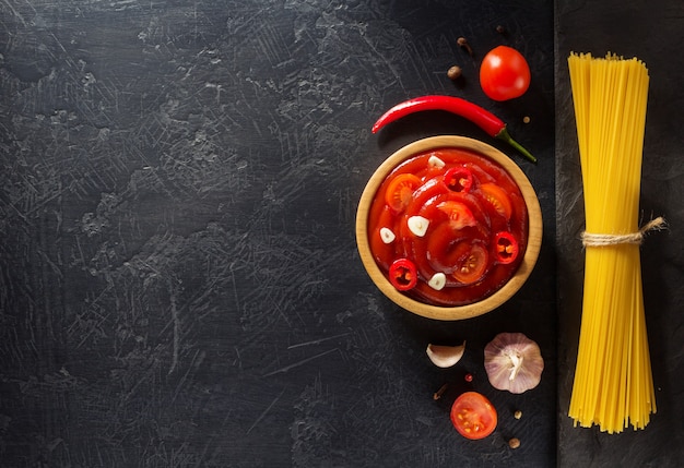 Tomato sauce in bowl on black texture