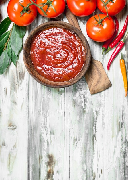 Tomato sauce in bowl with scoop bay leaf and hot pepper