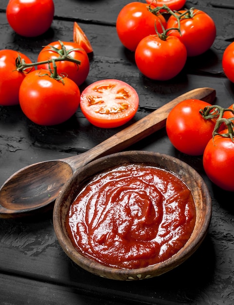 Foto salsa di pomodoro in ciotola con cucchiaio e pomodori maturi