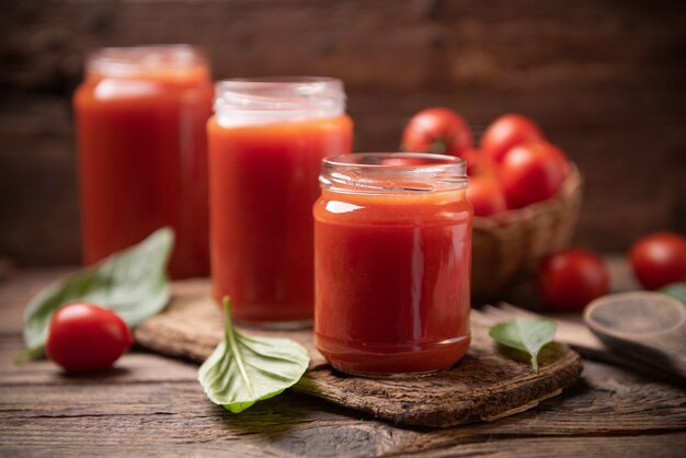 Tomato sauce in a glass jar on a rustic wooden table close up