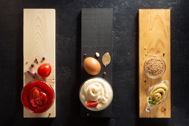 Tomato sauce, mayonnaise and mustard in bowl on wooden background