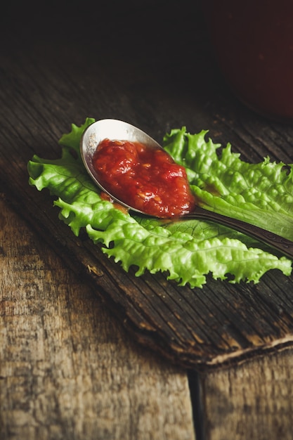 Salsa al pomodoro su un cucchiaio con le foglie della lattuga